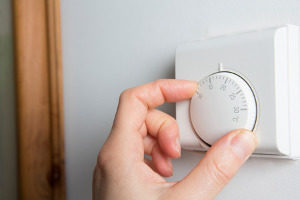 woman lowering the heating on her thermostat