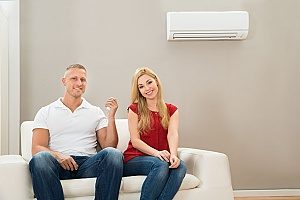 a couple relaxing next to their air conditioning unit that receives proper maintenance from a qualified HVAC contractor to improve their indoor air quality