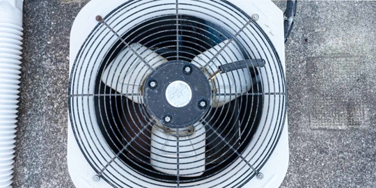 A white air conditioning unit with a black fan.
