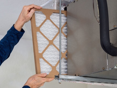 A person is replacing an air filter in a furnace.