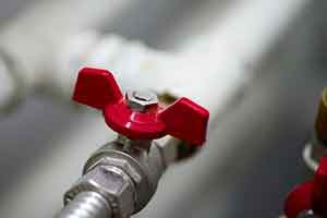 A close-up of a red valve on a water pipe
