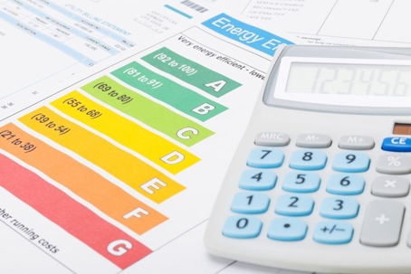 Energy efficiency ratings (A-G) and a calculator are on papers.
