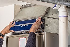 A person is replacing a filter on a furnace.