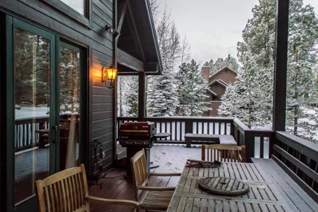 A snowy covered deck with a grill, table and chairs
