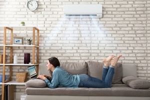 A woman is lying on a couch, using a laptop.