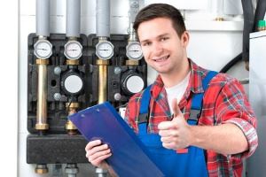A smiling technician in work clothes holds a clipboard and gives a thumbs-up.