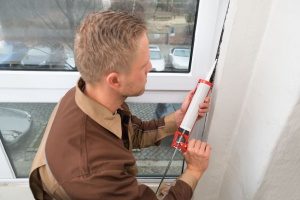 technician caulking a window in preparation for a Gaithersburg, MD HVAC maintenance