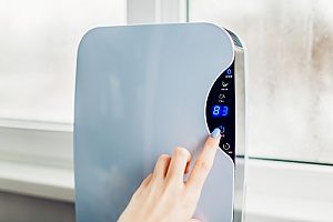 a woman using a dehumidifier to combat high humidity levels in her home