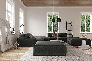 A light-filled room with dark gray sectional sofa, ottomans, and a wooden floor.