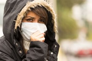 woman with a mask dealing with secondhand smoke indoors