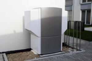 A gray and white utility box is mounted on the side of a building.