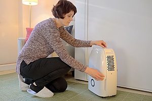 woman adjusting her brand new dehumidifier in order to lower the indoor humility level of her home and create optimal indoor air quality for her kids and dog