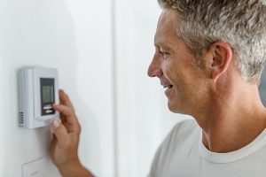 Man adjusting his heater to the exact temperature he wants after getting a new heat pump installed by a heating installation specialist 