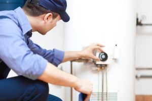 plumber fixing hot water heater as part of routine heating repair