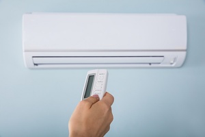 someone controlling a ductless vs. central air conditioner system