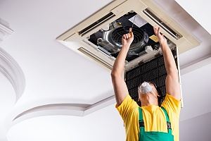 employee repairing a broken air conditioning during summer