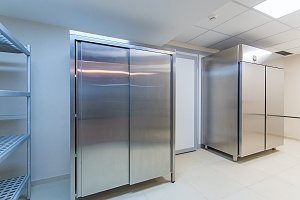 A stainless steel kitchen area with refrigerators and shelving.