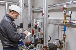 A worker in a hard hat is inspecting heating pipes and equipment.