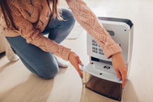 woman cleaning dehumidifier to achieve ideal home humidity