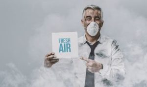 man wearing a surgical mask and holding a sign that reads fresh air