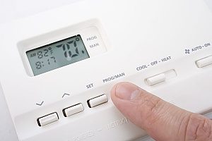 a man turning down his thermostat to allow his heating system to work during the winter