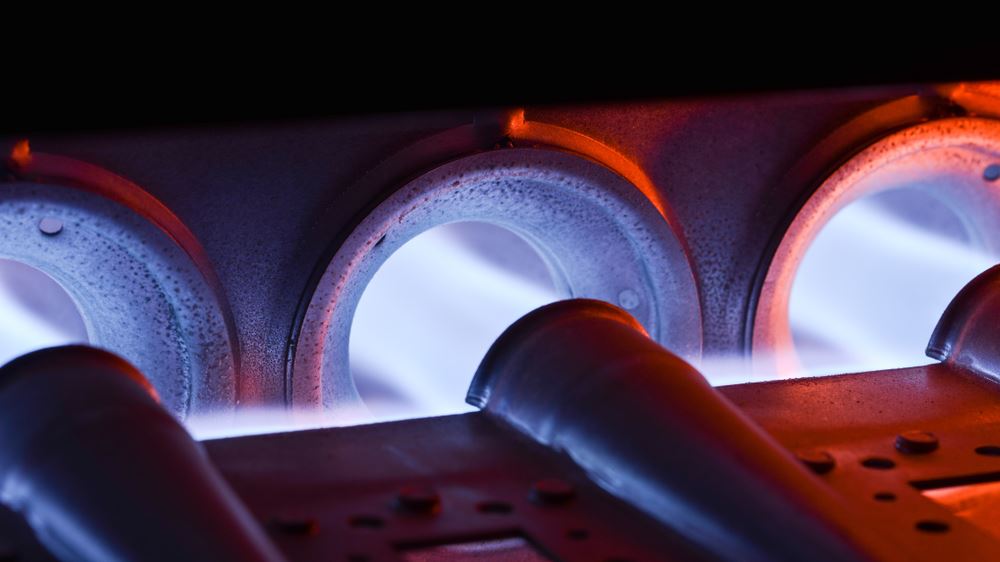 Three burners, glowing bright blue and orange, are emitting heat.