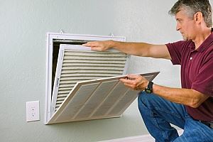 a homeowner replacing the air filter in a central air system