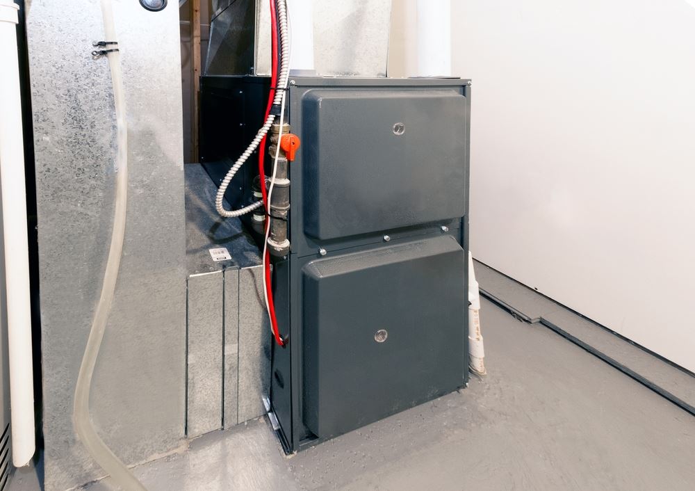 A dark gray furnace with pipes and vents is shown.