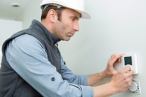 a Gaithersburg, MD HVAC contractor who is installing a new thermostat after conducting a full heating system replacement in a large modern home