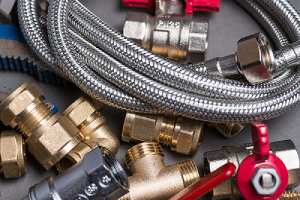 Assorted plumbing fittings and hose for dehumidifier on grey surface that has been repaired