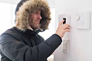 man checking thermostat because his heat wont turn on